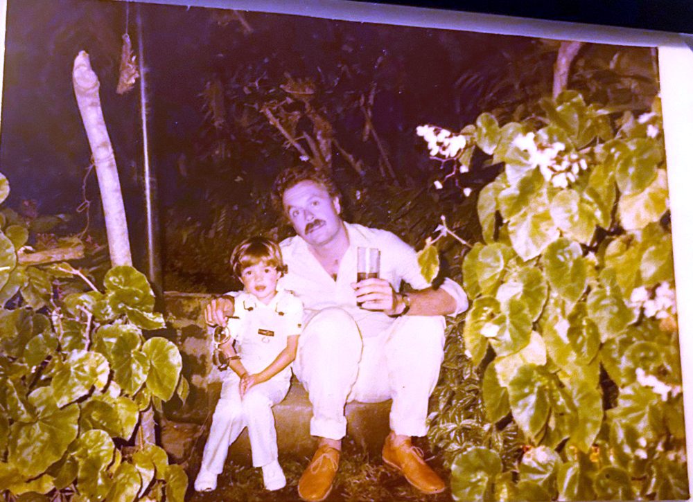 Choco crouching in a garden next to a small child in white